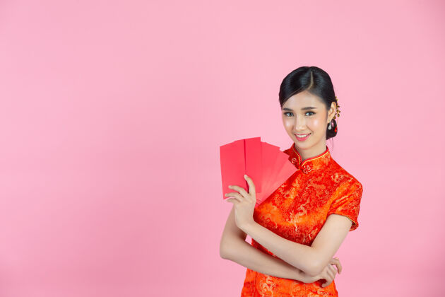 年轻美丽的亚洲女人在中国的新年里展示一些东西和拿红包人演示手势