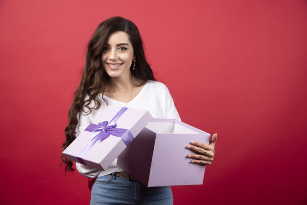盒子年轻女子拿着一个打开的红色背景礼物高质量的照片手持礼物人