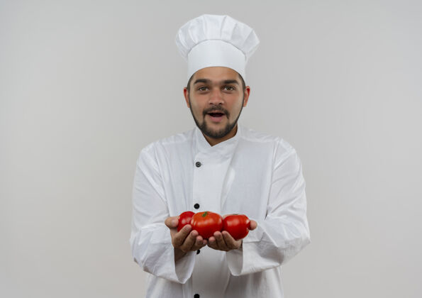 男性令人印象深刻的年轻男性厨师在厨师制服举行西红柿隔离在白色墙壁与复制空间番茄印象制服