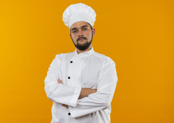 男性自信的年轻男性厨师身着厨师制服 站在封闭的姿势和孤立的橙色墙壁与复制空间姿势厨师封闭