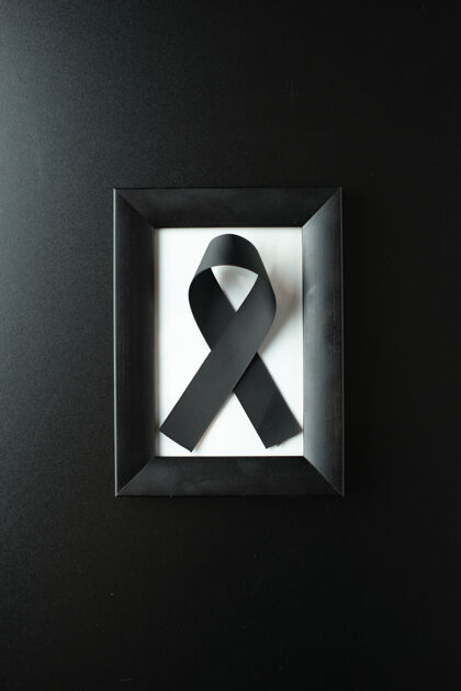 黑暗黑色墙壁上带黑色蝴蝶结的相框俯视图葬礼死亡视图