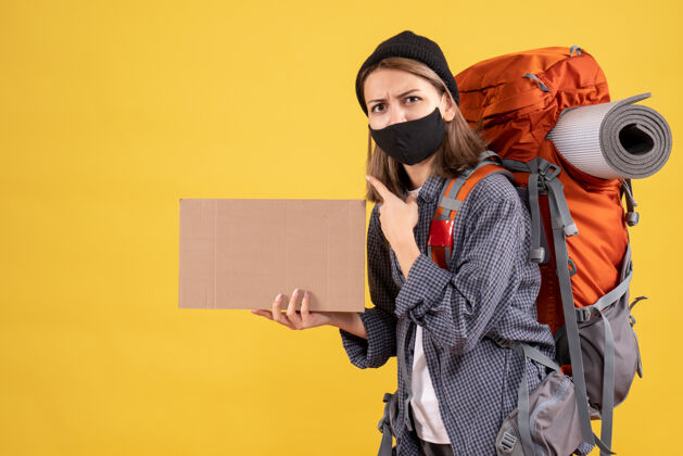 时尚带着黑色面具和背包拿着纸板的旅行女孩人男人面具