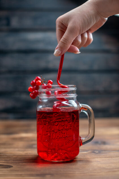 手正面图新鲜的蔓越莓汁里面可以用吸管在深色的吧台上水果照片鸡尾酒颜色的饮料蔓越莓糖浆里面水果