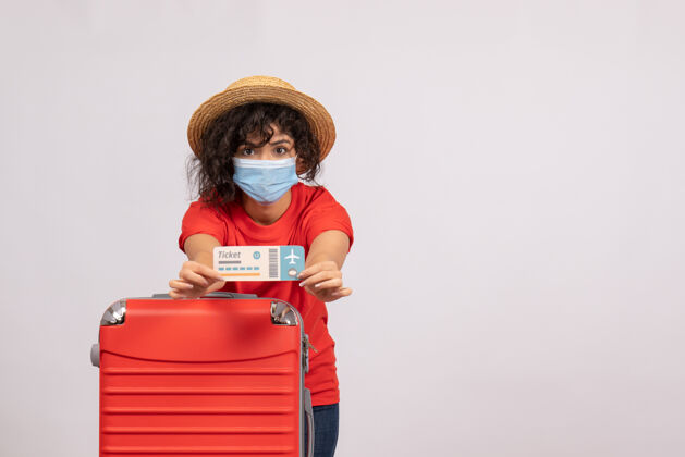年轻女性正面图年轻女性 戴着红包 戴着面具 拿着白色背景的机票 阳光普照 度假旅游的颜色人举行面具