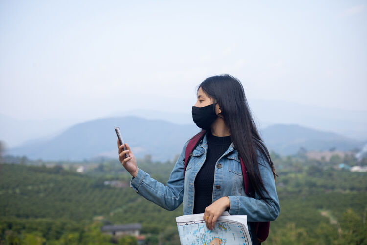 女人亚洲女游客戴着口罩看手机女孩地图预防