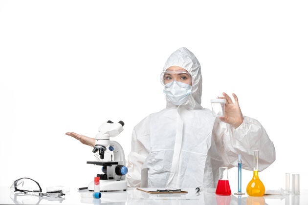 病毒正面图：年轻女医生穿着防护服 戴着口罩 白色背景上有一个装着病毒的瓶子大流行医生口罩
