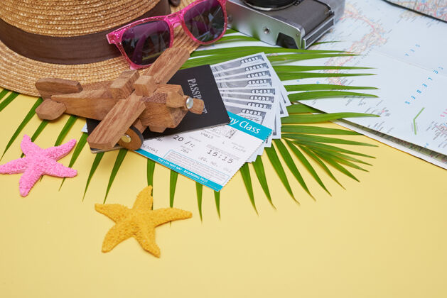 笔记本在黄色表面上平铺旅行配件 带棕榈叶 相机 鞋 帽子 护照 钱 机票 飞机和太阳镜顶视图 旅行或度假概念平板时尚手机