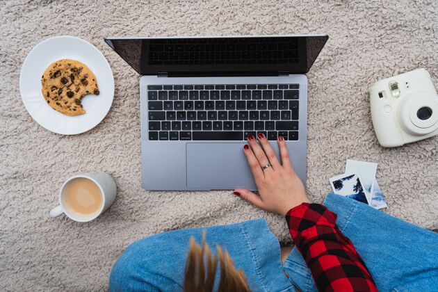桌子一个女人坐在毯子上拿着笔记本电脑和咖啡的水平镜头工作自然室内