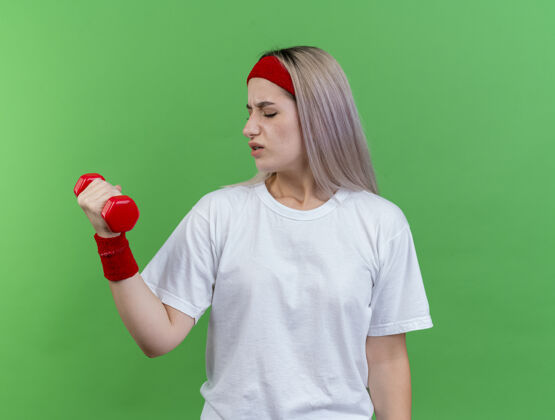 复制年轻的白人运动女孩戴着背带 戴着头带和腕带 手持哑铃哑铃背带头带