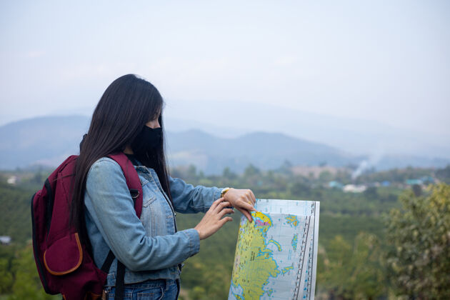 游客亚洲女游客戴着口罩看手表探索预防地图
