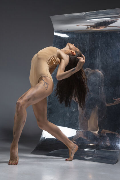 灵活年轻时尚的现代芭蕾舞演员在灰色的墙壁上 镜子和幻觉反射在表面帅气表演时尚