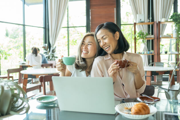 朋友女学生在当地咖啡馆学习两个女学生一边喝咖啡一边在咖啡馆讨论商业项目创业 创意和头脑风暴概念在咖啡馆用笔记本电脑和热饮微笑的朋友房子工作手机