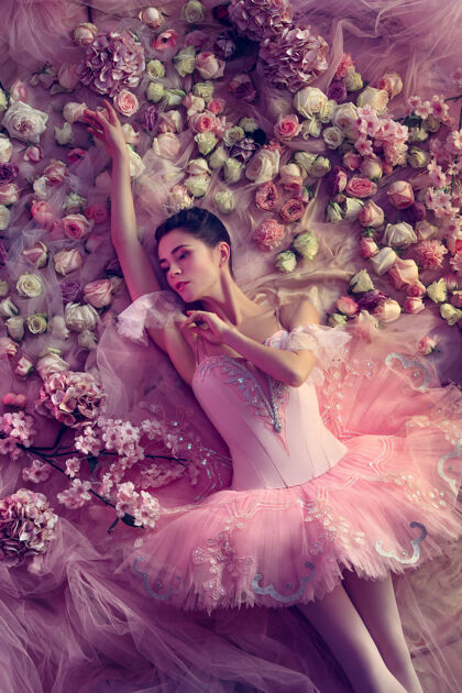 模特俯瞰美丽的年轻女子在粉红色芭蕾舞团图图周围的鲜花艺术灵活春天