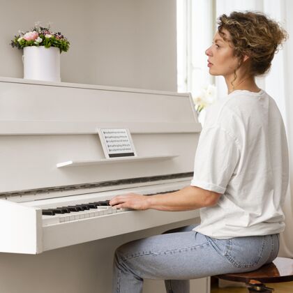 女人一个金发女钢琴的侧视图和平钢琴音乐家