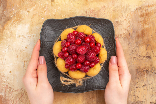 健康在混合色背景上的棕色盘子上新鲜烘焙的礼品蛋糕的俯视图新鲜水果可口