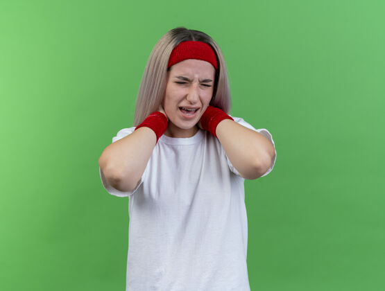背带疼痛的年轻白人运动女孩戴着背带和头带腕带年轻头带