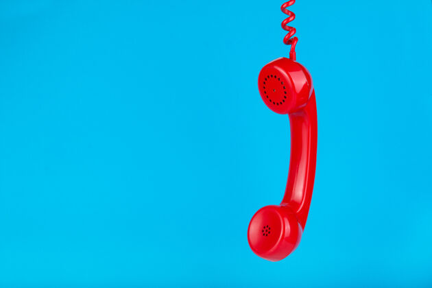 资源旧的红色电话听筒挂在蓝色的表面上老科技戒指