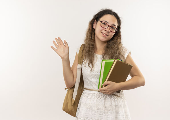 人面带微笑的年轻漂亮的女学生戴着眼镜 背着书包 在隔离在白色墙上的门前挥手致意人感觉脸