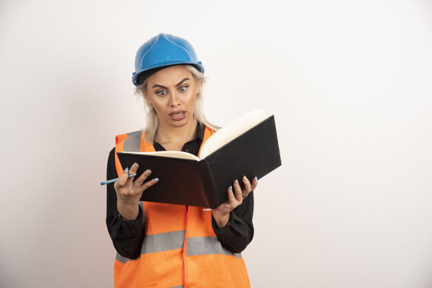 背心惊讶的工人阅读白色背景上的笔记高品质的照片女人建筑头盔