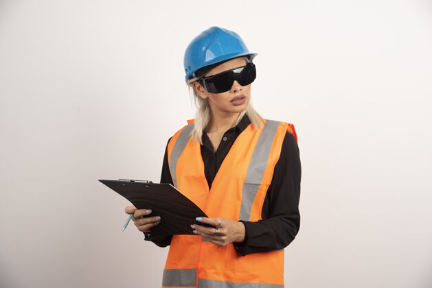 女性带护目镜和剪贴板的女建筑工人高质量的照片制服人类铅笔
