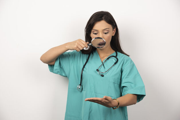 工人女医生用放大镜紧张地看着她的手高质量的照片医疗放大镜保健