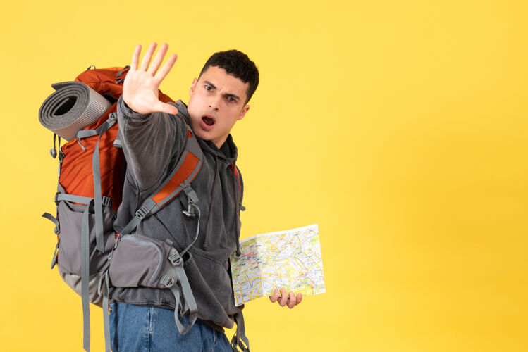 视图前视图旅行者男子背着背包拿着地图做停车标志人前面成人