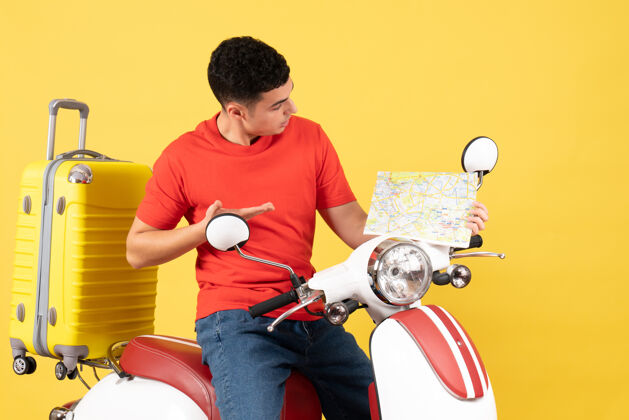 男人正面图穿着休闲服的年轻人坐在轻便摩托车上看旅游地图视图旅行男性