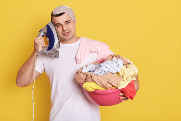 电年轻英俊的白人男子拿着洗过的新衣服脸盆家庭生活设备衣服