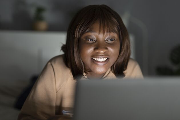 舒适笑眯眯的非洲裔美国女人在家看netflix手表流电视