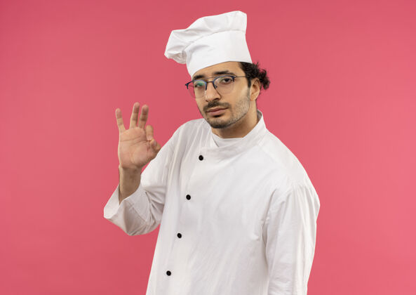 厨师看着镜头 年轻的男厨师穿着厨师制服 戴着眼镜 摆出很好的姿势男性背景表演