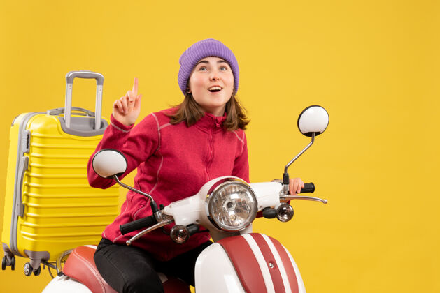 快乐前视图：骑着轻便摩托车的年轻女子手指向上前面摩托车年轻女子
