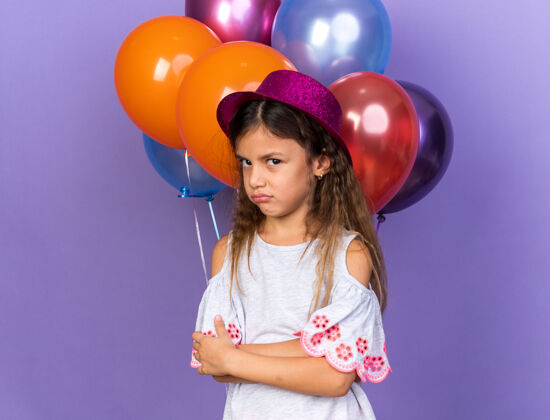 帽子恼怒的小白种女孩戴着紫色的聚会帽交叉双臂站在氦气球前 氦气球被隔离在紫色的墙上 留着复制空间站小孤立