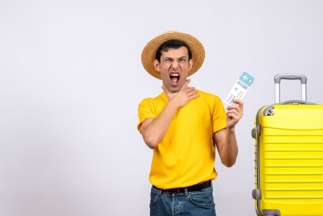年轻游客正面图身穿黄色t恤的年轻游客手持机票站在黄色手提箱旁帽子抱着人
