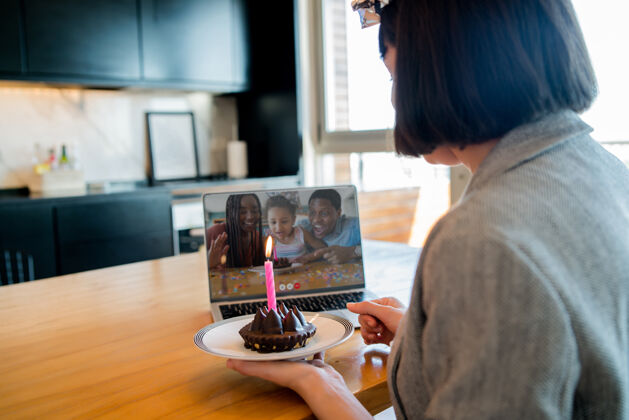 女人年轻女子在家里用笔记本电脑和蛋糕通过视频通话庆祝生日的画像聊天互联网通信