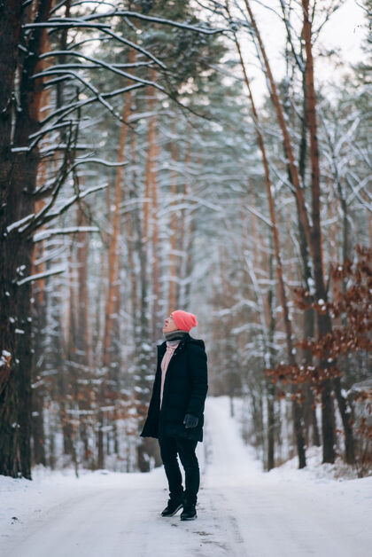 人小伙子站在森林中间被雪包围的路上长沥青骑