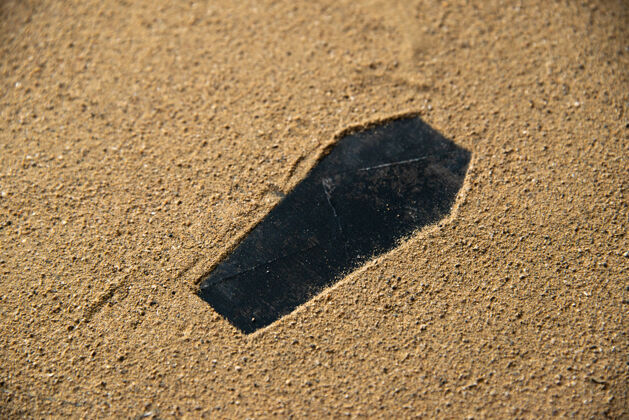 刀片在沙子上做的黑色棺材形状石头表面纹理