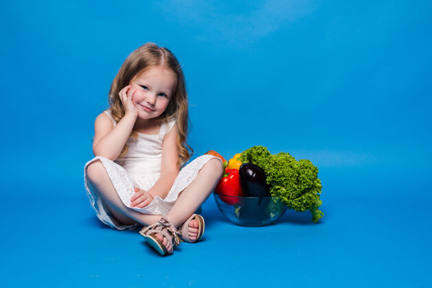 女孩蓝色墙上挂着蔬菜的小女孩小女孩可爱蔬菜
