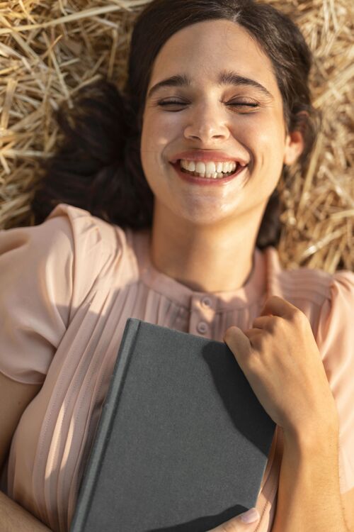 年轻快乐的女人拿着书放松快乐自然