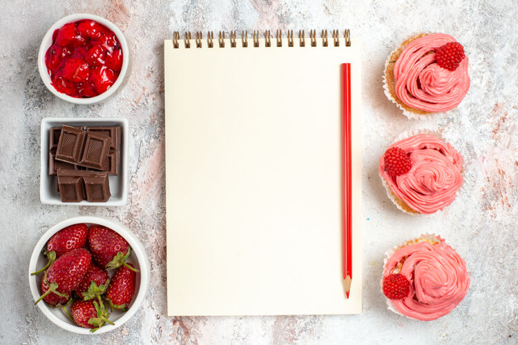 茶白色表面上有奶油的粉色草莓蛋糕俯视图记事本容器边框