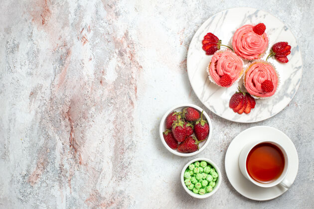 甜点白色表面上有茶的粉色草莓蛋糕俯视图新鲜饼干玫瑰