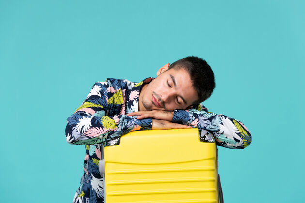 假期年轻男性正准备度假 黄色的袋子感觉很累 睡在蓝色的墙上男人准备包