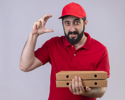送货年轻帅气的送货员身穿红色制服 头戴鸭舌帽 手里拿着披萨盒 在白色的墙上展示着与世隔绝的尺寸表演人穿着