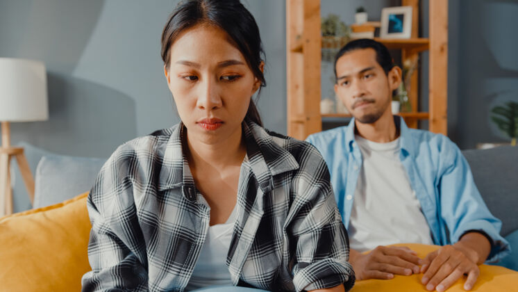 抑郁心烦意乱的亚洲夫妇坐在客厅的沙发上麻烦男人女性