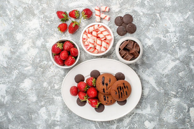 椭圆形顶视饼干草莓和圆形巧克力在白色椭圆形盘子碗糖果草莓巧克力在灰白色的桌子中央可食用水果盘子水果