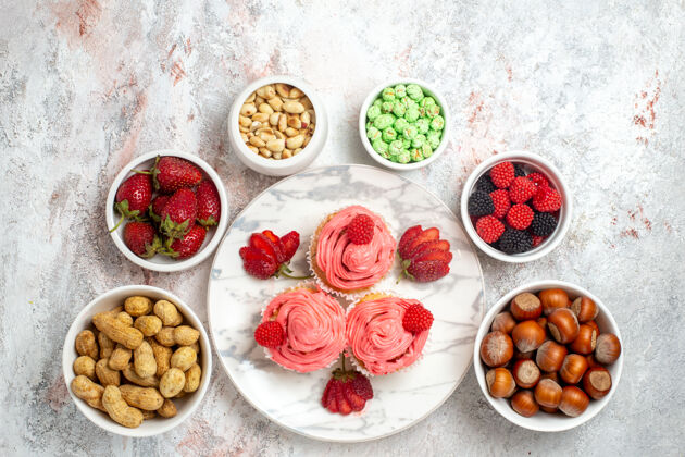 糖白色表面有坚果和糖果的粉色草莓蛋糕俯视图胡椒粉食物提神