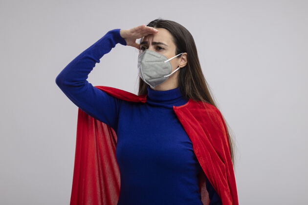 年轻年轻的超级英雄女孩戴着医用口罩望着远处用手隔离着白色距离医疗穿着
