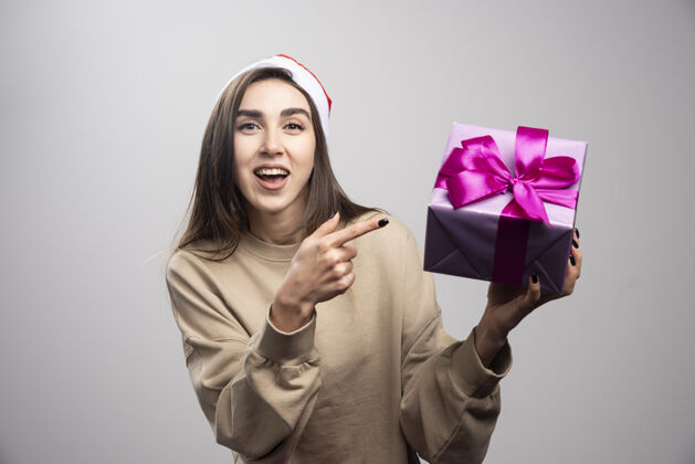 漂亮微笑的女人指着一盒圣诞礼物女性兴奋圣诞老人