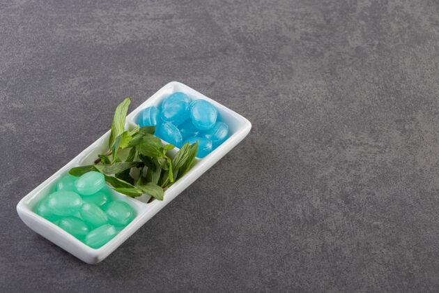 美味蓝色和绿色的硬糖在碗里放在石桌上绿色糖果可口