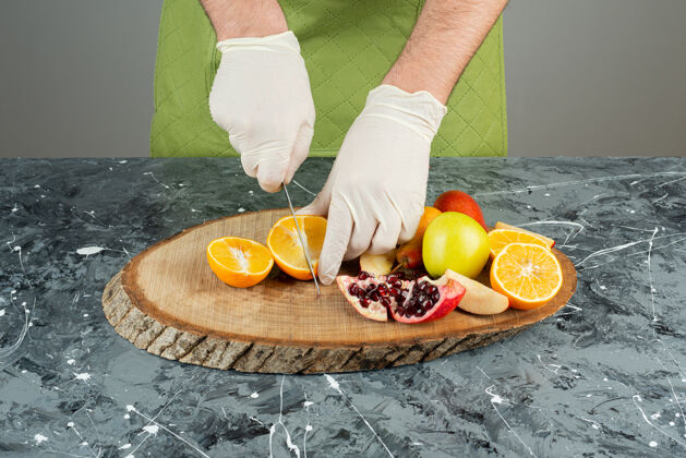 橙子男性手戴手套在大理石桌上切橘子汁各种准备烹饪