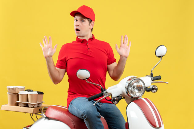 身体前视图好奇的年轻人穿着红色衬衫和帽子 在黄色背景下传递命令健身背景年轻人